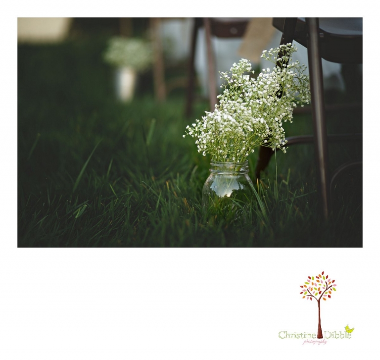 A spray of baby's breath in a Mason jar decorates the aisle at a ceremony site for a wedding at Don Pedro Hacienda photographed by photographer Christine Dibble Photography of Sonora