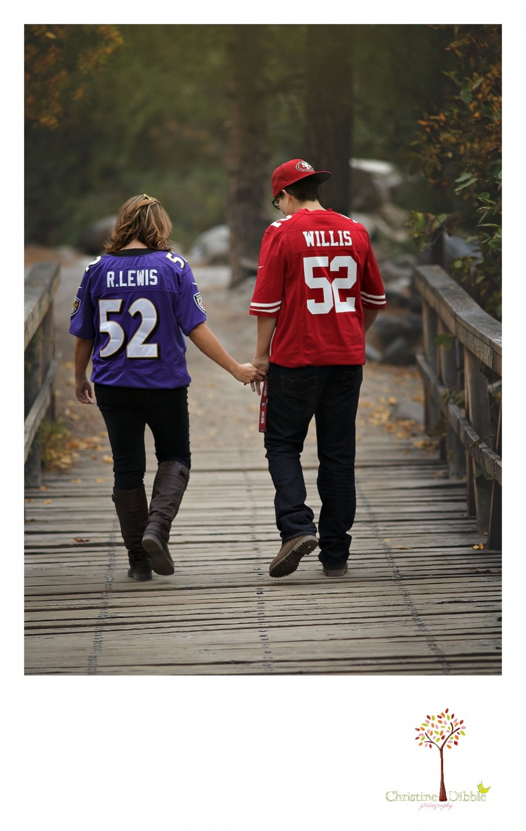 Sonora and Reno family and wedding photographer Christine Dibble Photography photographs a couple in rival football jerseys as they cross a bridge in Galena Park.