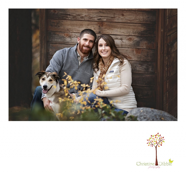 Sonora and Reno family and wedding photographer Christine Dibble Photography photographs a portrait of an engaged couple and their dg as they sit in front of a rustic wooden building at Galena Park.