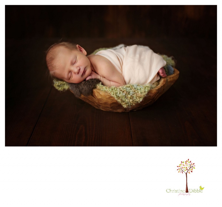 Sonora newborn photographer Christine Dibble Photography takes photos of a baby girl in a wooden bowl filled with layering pieces.