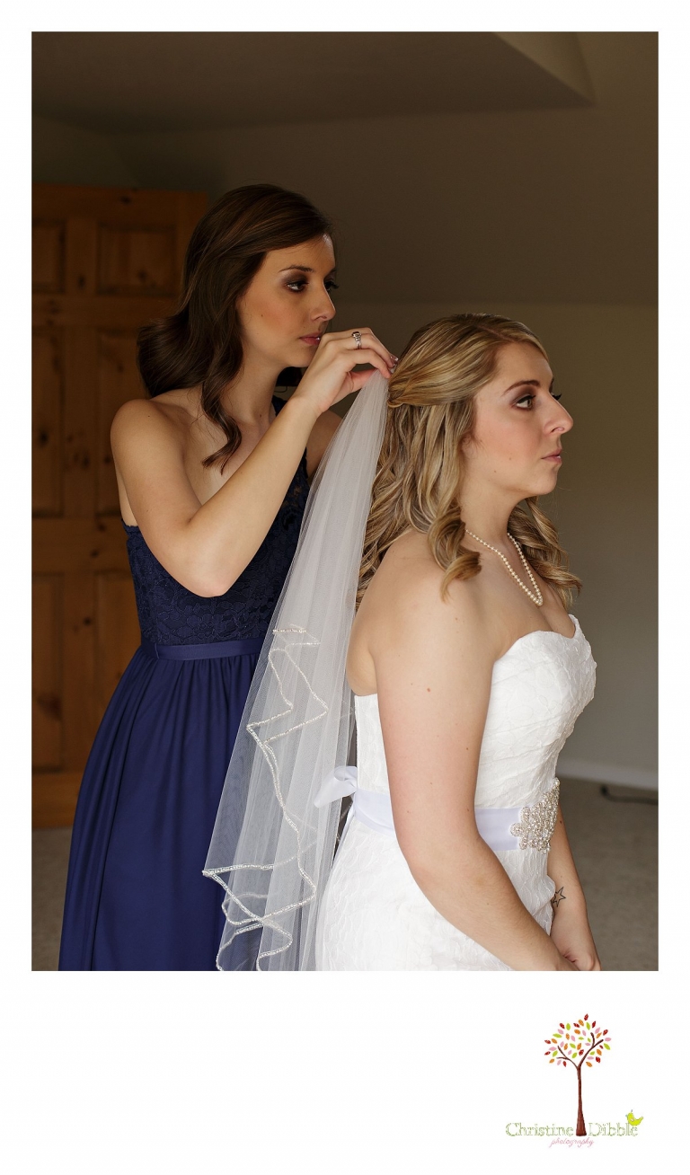 Sonora, CA wedding photography by Christine Dibble Photography captures a maid of honor, and the bride's sister, putting the bride's veil into her hair.