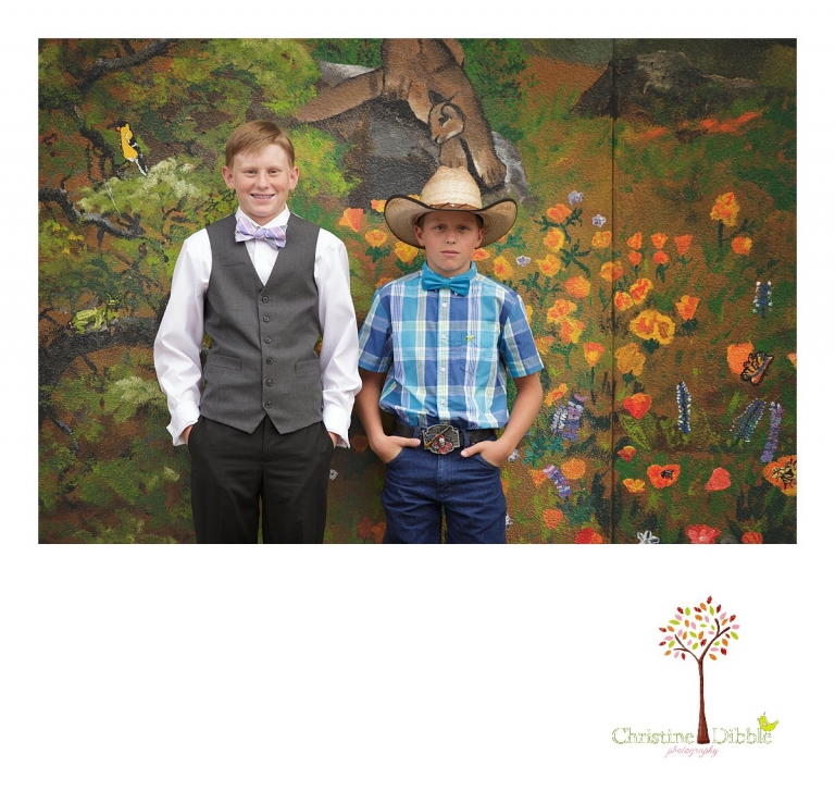 Sonora graduation and senior portrait photographer Christine Dibble Photography takes eighth grade graduation photos of a cowboy in front of the mural wall with a fellow graduate.