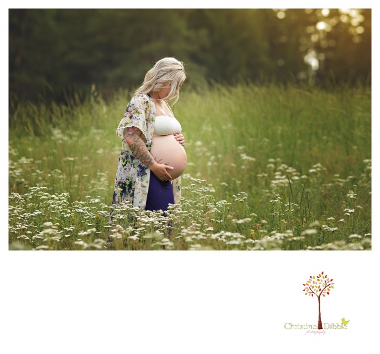 Sonora maternity photographer Christine Dibble Photography takes pregnancy photos of a mom standing in a grassy field of wildflowers at sunset.