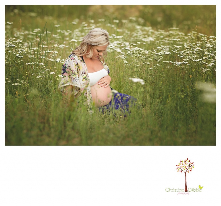 Sonora maternity photographer Christine Dibble Photography takes pregnancy belly photos of a woman sitting among white wildflowers.