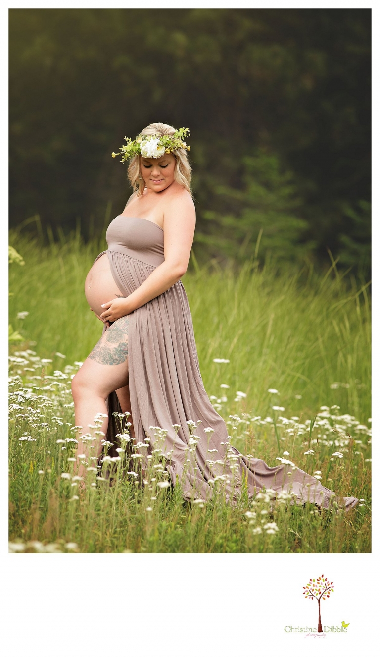 Sonora maternity photographer Christine Dibble Photography takes pregnant belly portraits of a mother with tattoos in a belly dress and floral headpiece wreath in a field of white wildflowers.