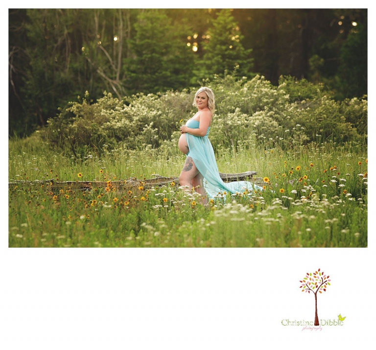Sonora maternity photographer Christine Dibble Photography takes belly bump photos of a mom with tattoos in a wildflower field in the woods.