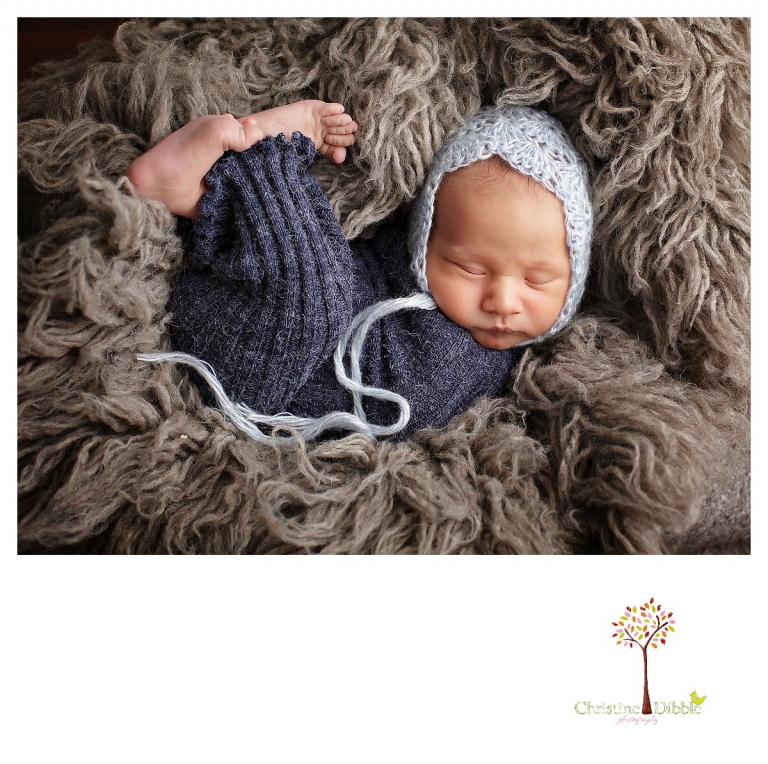 Sonora newborn and baby photographer Christine Dibble Photography takes indoor studio portraits of a sleeping baby boy in a newborn sock and bonnet and on a flokati rug.
