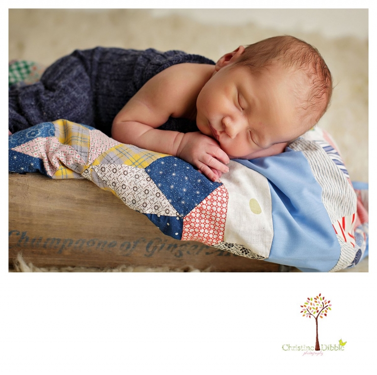 Sonora newborn and baby photographer Christine Dibble Photography takes indoor studio portraits of a baby boy sleeping in an antique crate on a vintage quilt top.