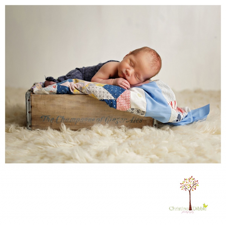 Sonora newborn and baby photographer Christine Dibble Photography takes indoor studio portraits of a baby boy sleeping on an antique quilt in an antique wooden box.