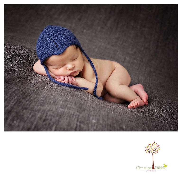 Newborn photography by best Sonora newborn photographer Christine Dibble Photography takes studio portraits of a baby boy in a blue crochet hat on a gray blanket.