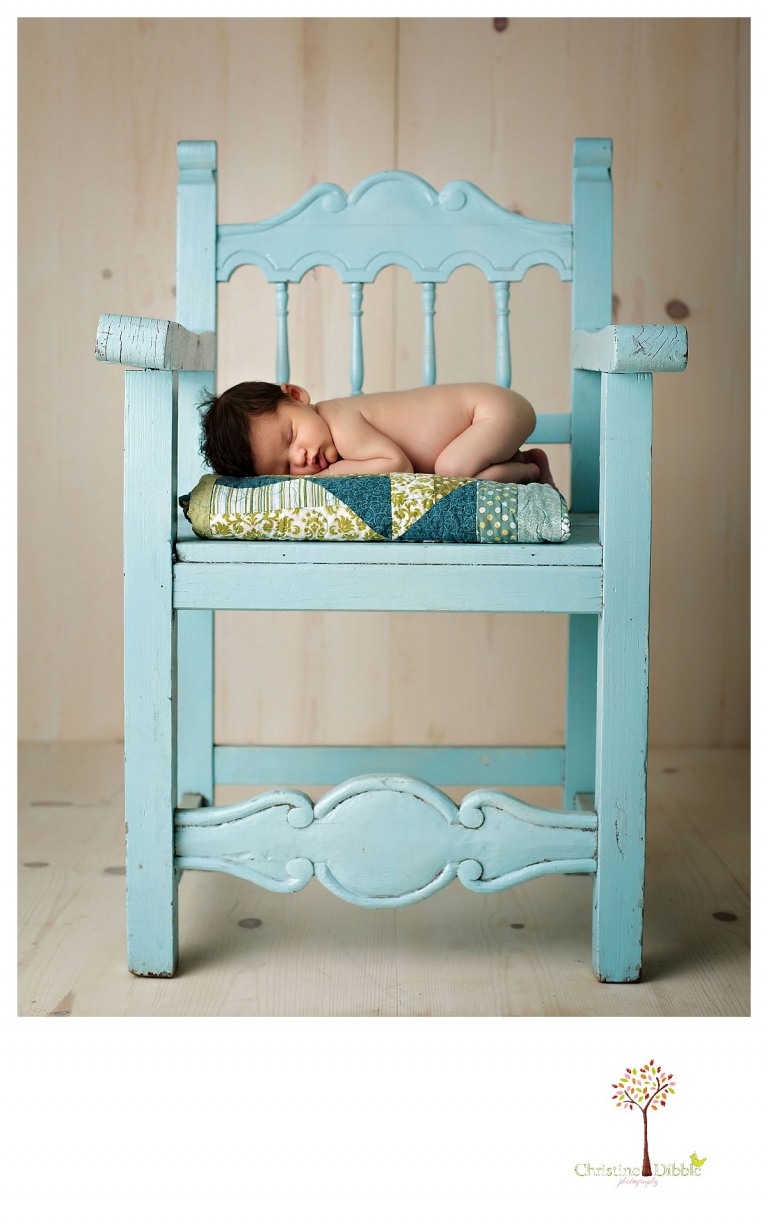 Newborn photography by best Sonora newborn photographer Christine Dibble Photography takes studio portraits of a baby boy sleeping on a quilt on a turquoise chair.