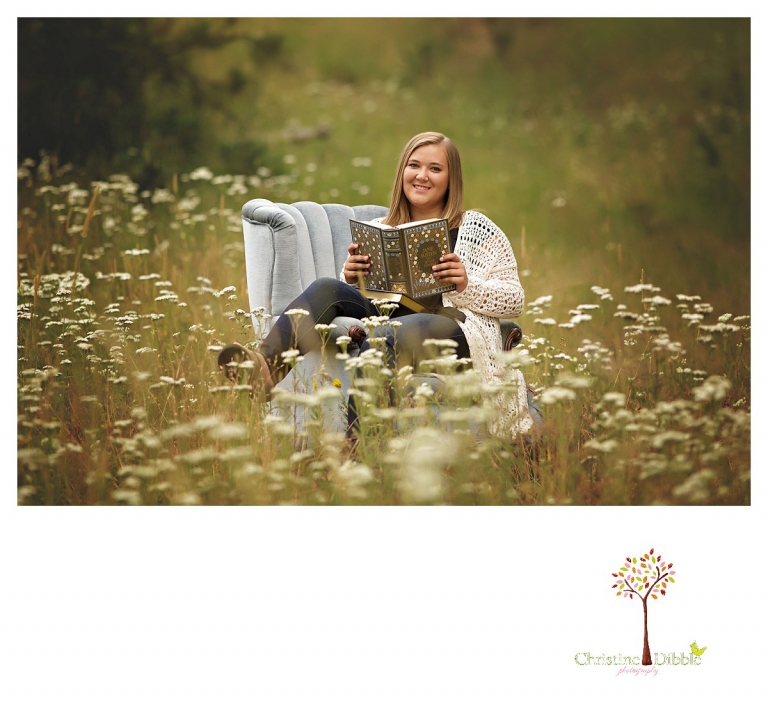 Sonora and Summerville senior portrait photographer Christine Dibble Photography takes outdoor senior portraits of a girl as she reads in a blue velvet chair in a field of flowers.
