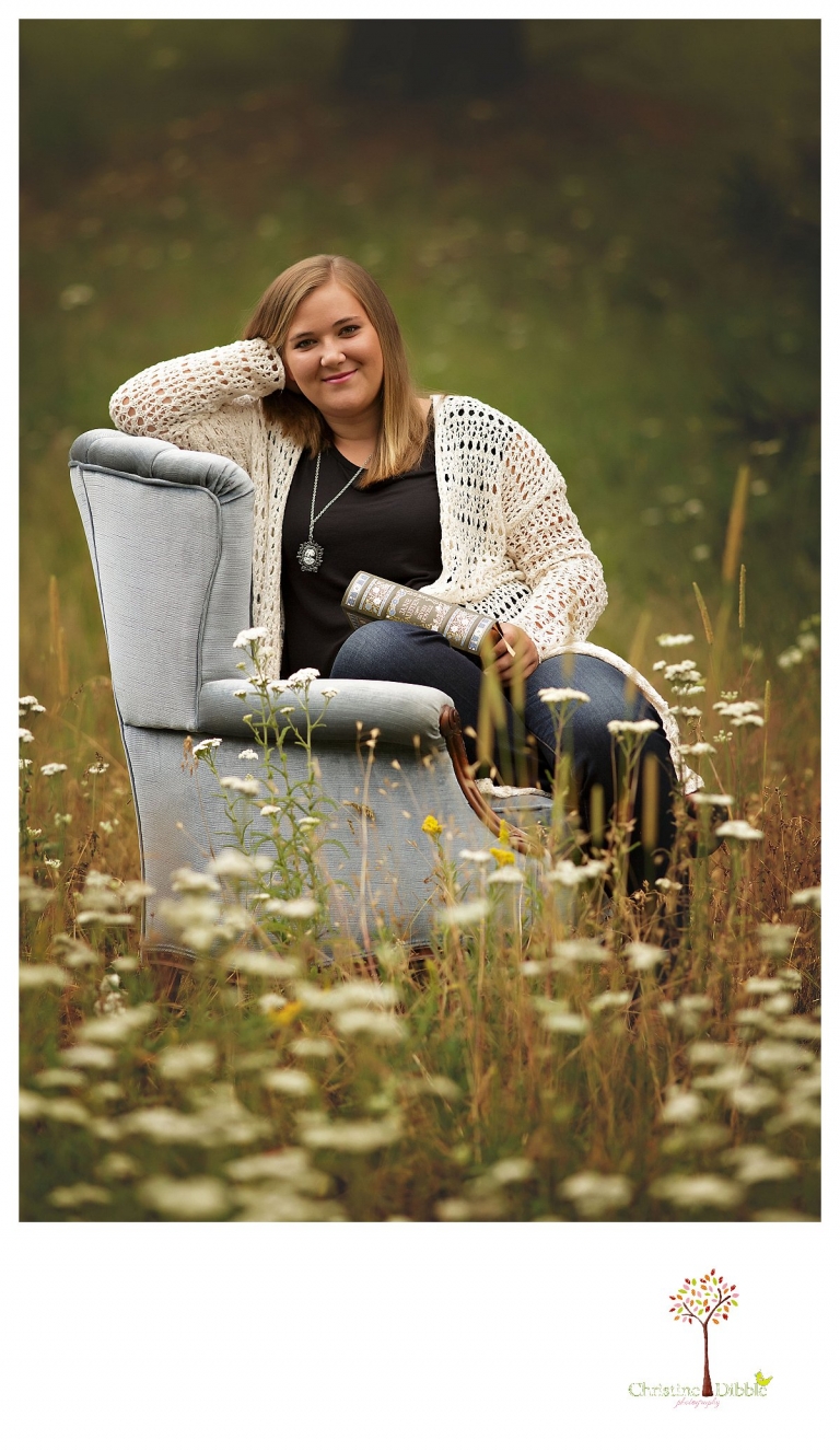 Sonora and Summerville senior portrait photographer Christine Dibble Photography takes outdoor senior portraits of a girl sitting in a plush chair in a field of flowers.