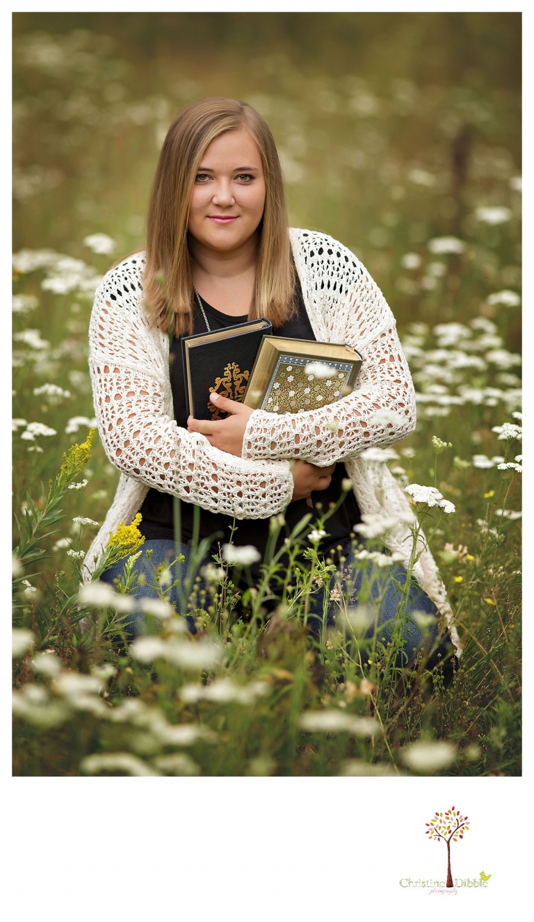 Sonora and Summerville senior portrait photographer Christine Dibble Photography takes outdoor senior portraits of a girl with her books in a flower field.