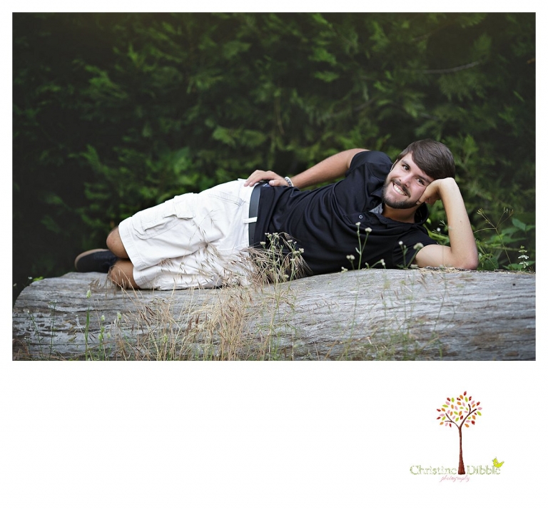 Sonora and Summerville senior portrait photographer Christine Dibble Photography takes senior portraits of a boy at Twain Harte Tree Farm as he strikes a silly cover girl pose on a log.