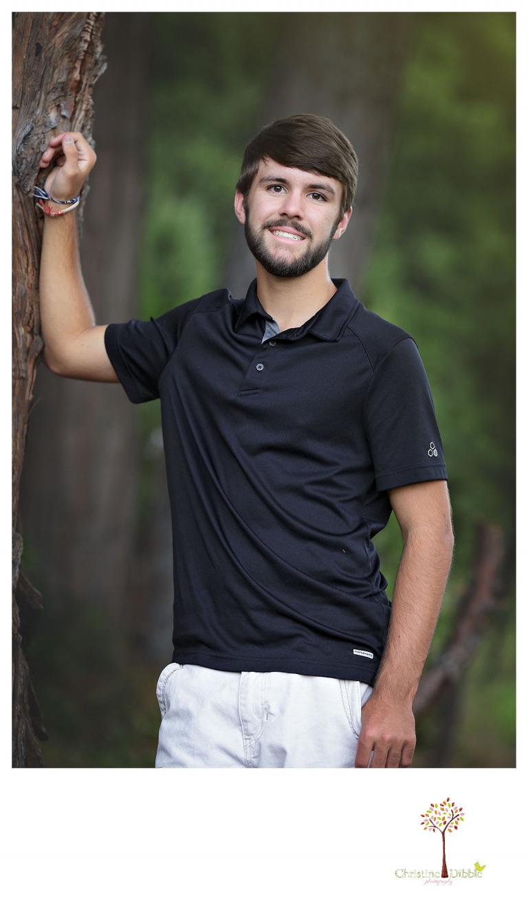 Sonora and Summerville senior portrait photographer Christine Dibble Photography takes senior portraits of a boy leaning on a tree trunk at  Twain Harte Tree Farm.