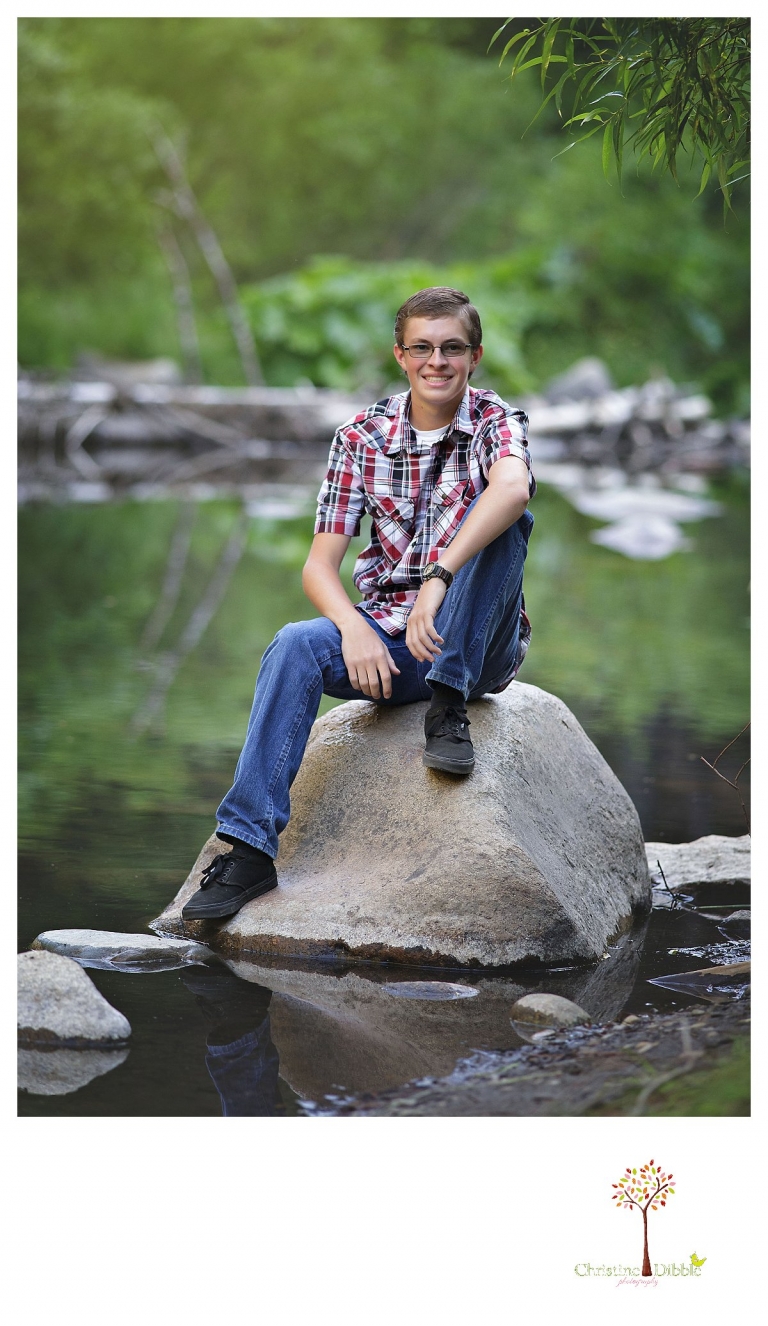 Christine Dibble Photography, Summerville and Sonora senior portrait photographer, takes photos of a boy on a rock in a river.