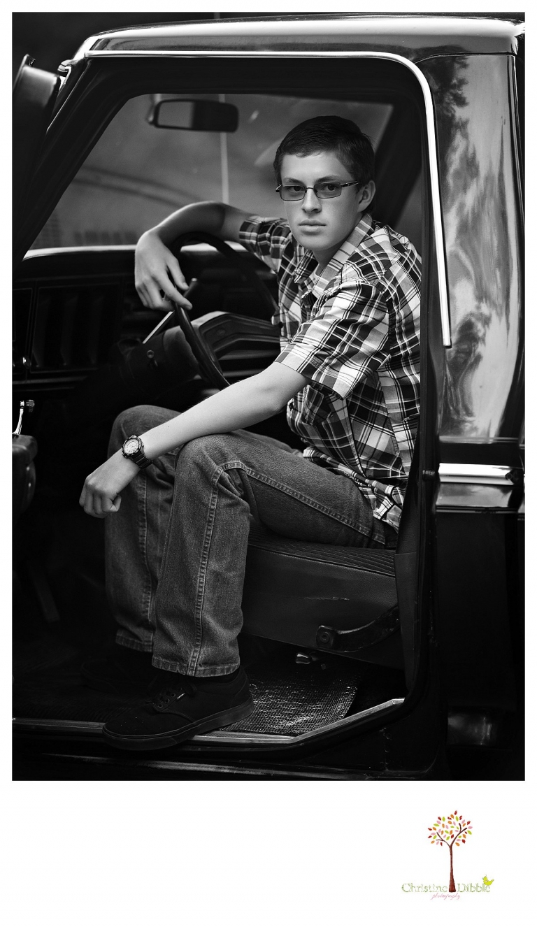 Christine Dibble Photography, Summerville and Sonora senior portrait photographer, takes photos in black and white of a boy in his old black Chevy truck.