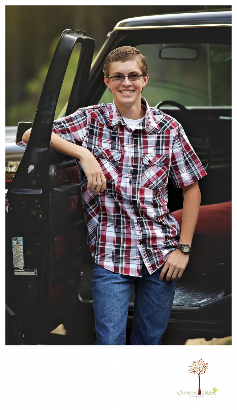 Christine Dibble Photography, Summerville and Sonora senior portrait photographer, takes photos of a boy standing with his old black Chevy truck.