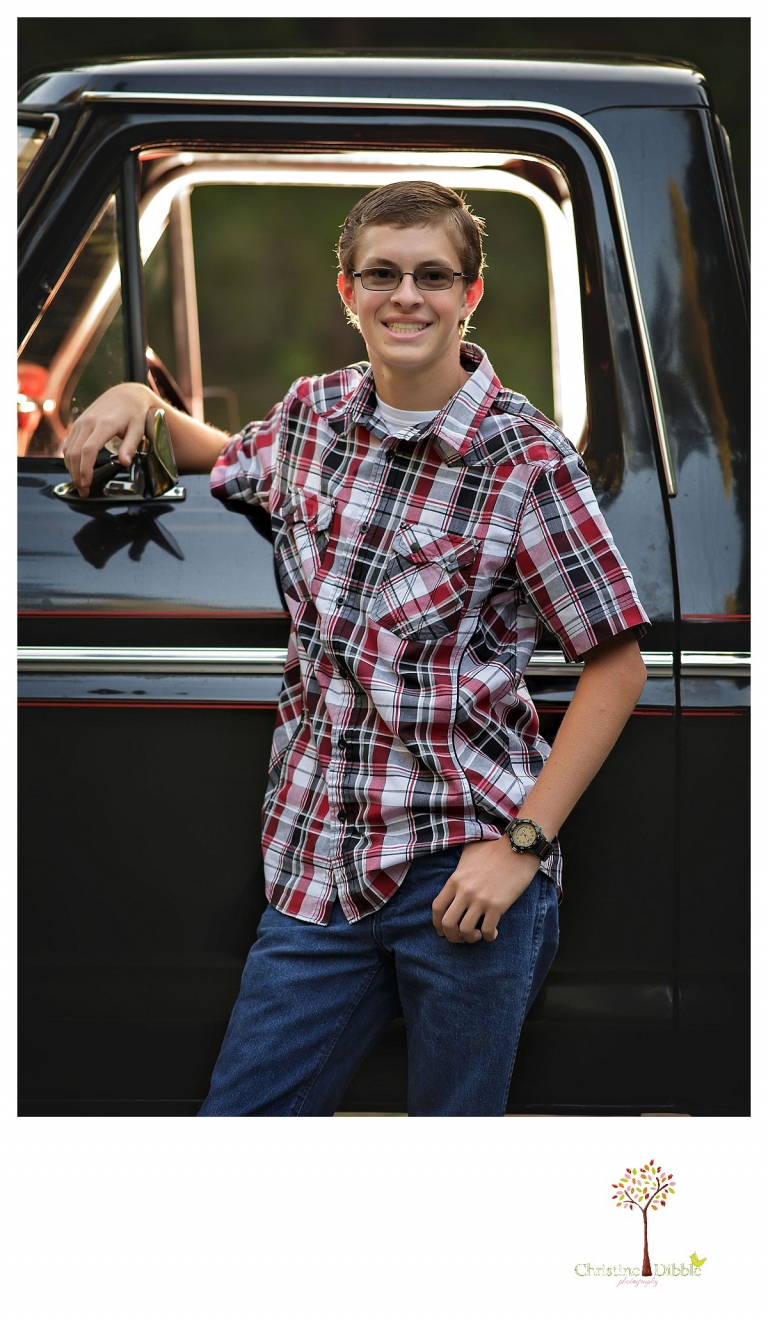Christine Dibble Photography, Summerville and Sonora senior portrait photographer, takes photos of a boy by his black Chevy truck with the cab lit.