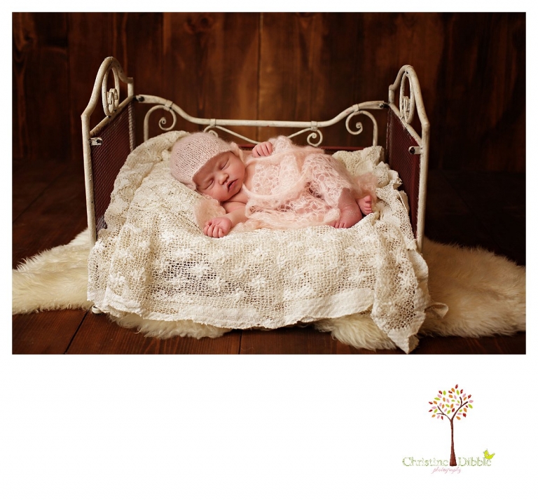 Newborn photography by Sonora photographer Christine Dibble Photography photographs a newborn baby girl sleeping in mohair on an antique tablecloth on a miniature iron bed.