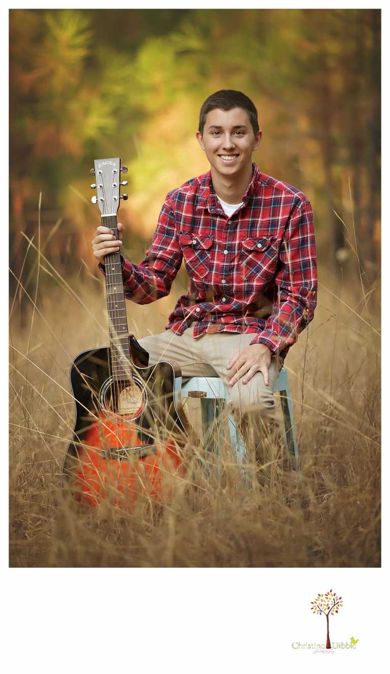 A senior from Summerville High School smiles with his guitar during a senior portrait session with Christine Dibble Photography of Sonora.