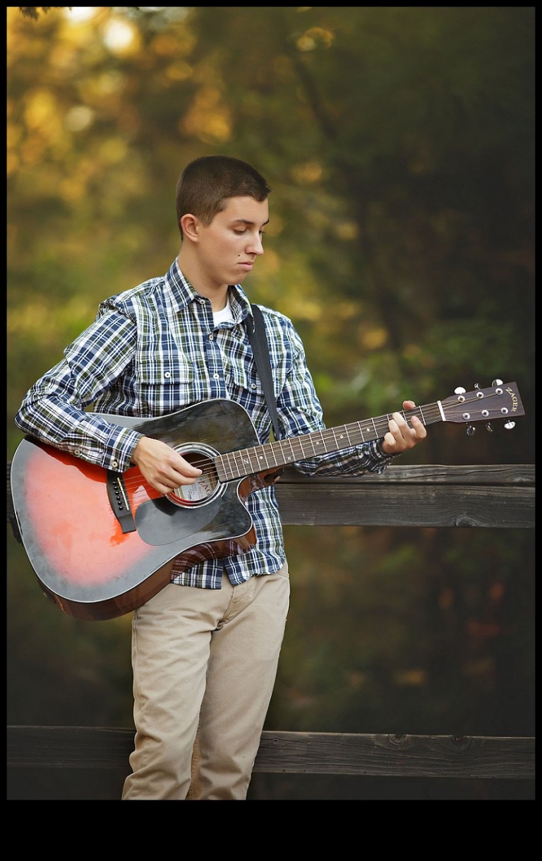 A Summerville senior plays his guitar under tall pine trees during a senior portrait session with Christine Dibble Photography of Sonora.