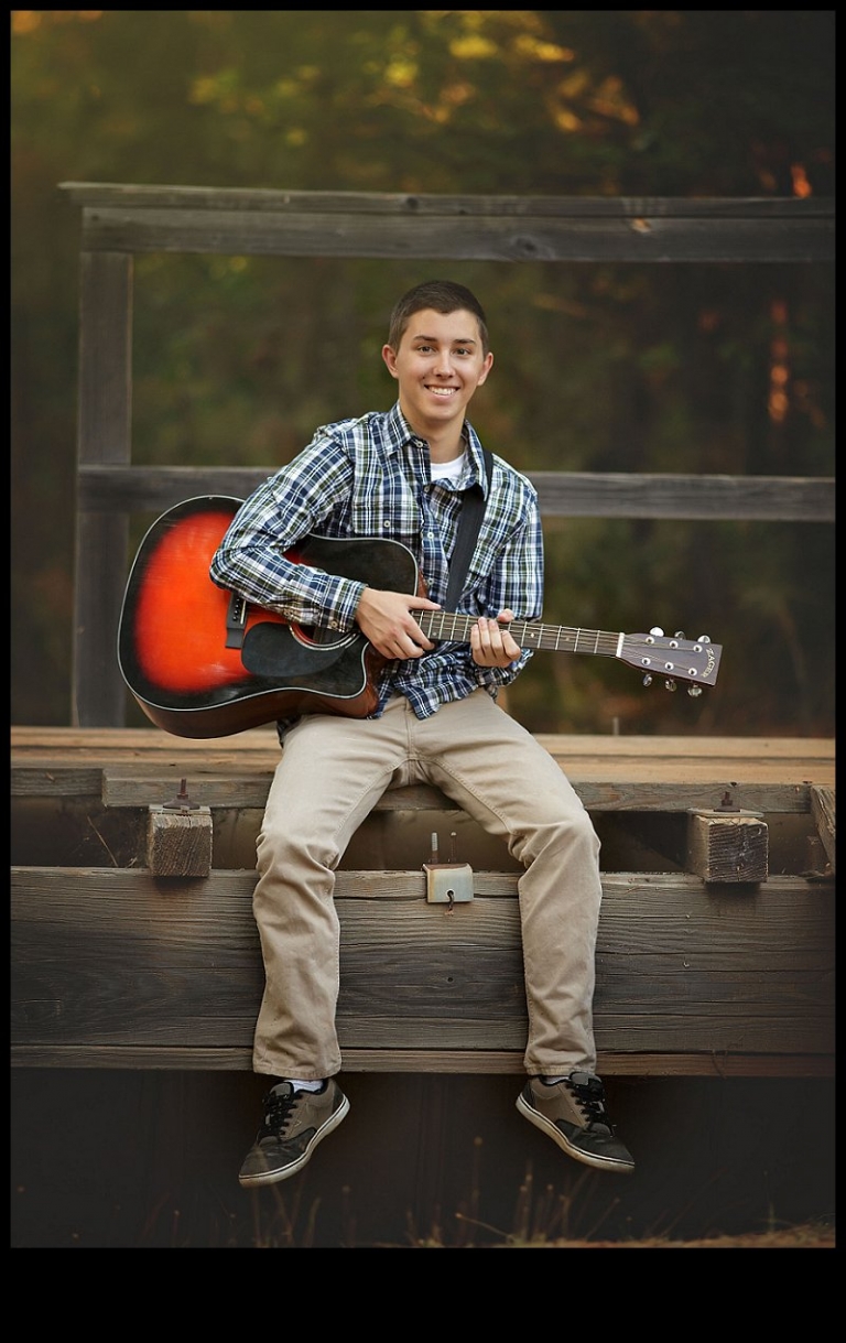During a senior portrait session with Christine Dibble Photography of Sonora, a Summerville High senior boy site on a trestle with his guitar.