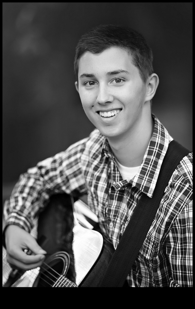 A black and white portrait is taken of a Summerville High senior boy with his guitar during a senior portrait session with Christine Dibble Photography of Sonora.