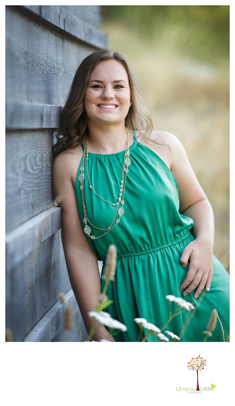 Senior portraits in Sonora taken of a Summerville Class of 2016 senior by Christine Dibble Photography near a rustic wooden wall and a flower field.