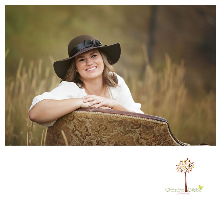Summerville and Sonora senior portrait photographer Christine Dibble Photoraphy takes outdoor senior portraits of a girl in a floppy hat in an antique chair in a field.