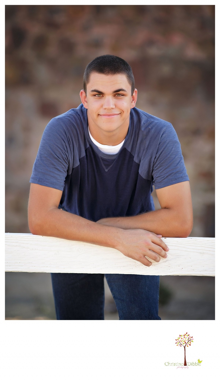 Summerville senior portrait photographer, Christine Dibble Photography of Sonora, takes photos of a senior boy at Knights Ferry as he leans on a fence.