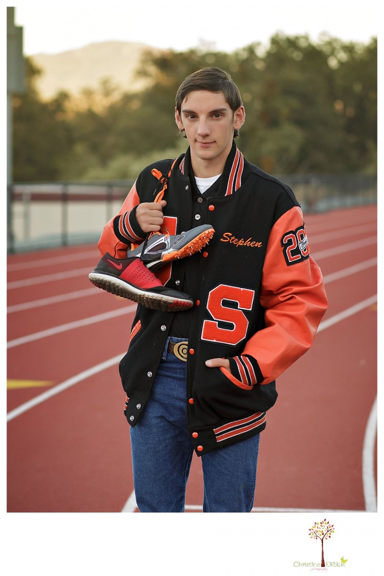 Summerville High and Sonora senior portrait photographer Christine Dibble Photography takes outdoor senior portraits of a varsity track athlete with his spikes and letterman jacket.