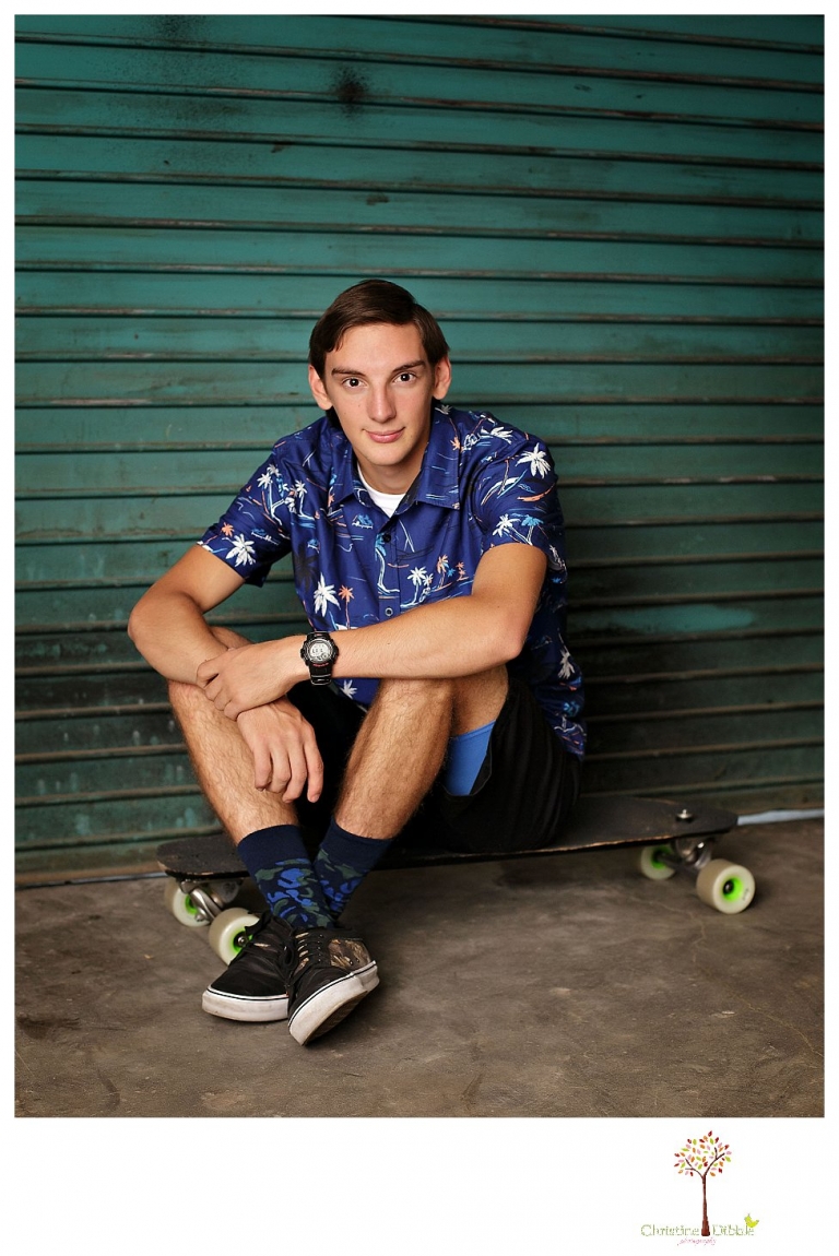 Summerville High and Sonora senior portrait photographer Christine Dibble Photography takes studio senior portraits of a boy and his skateboard in front of a turquoise door.