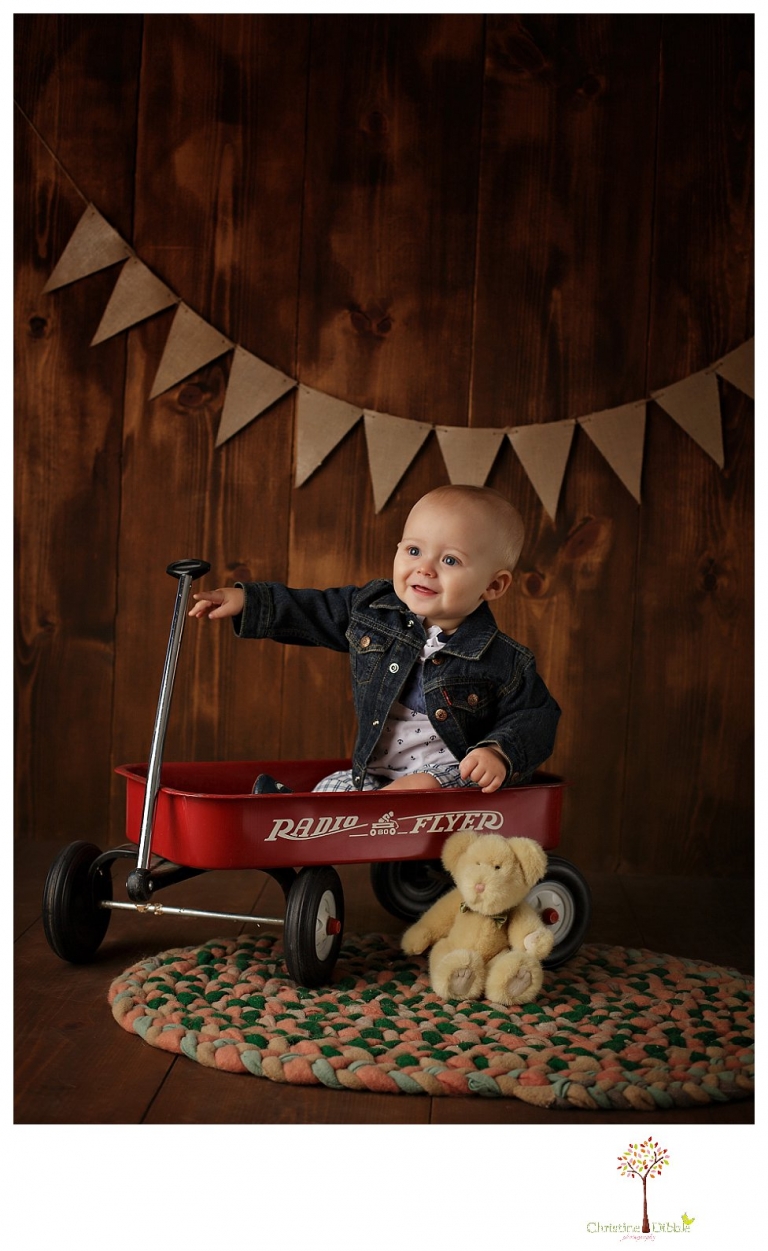Sonora baby and child photographer Christine Dibble Photography takes first year portraits in her studio of a little boy with a red wagon and vintage accessories.