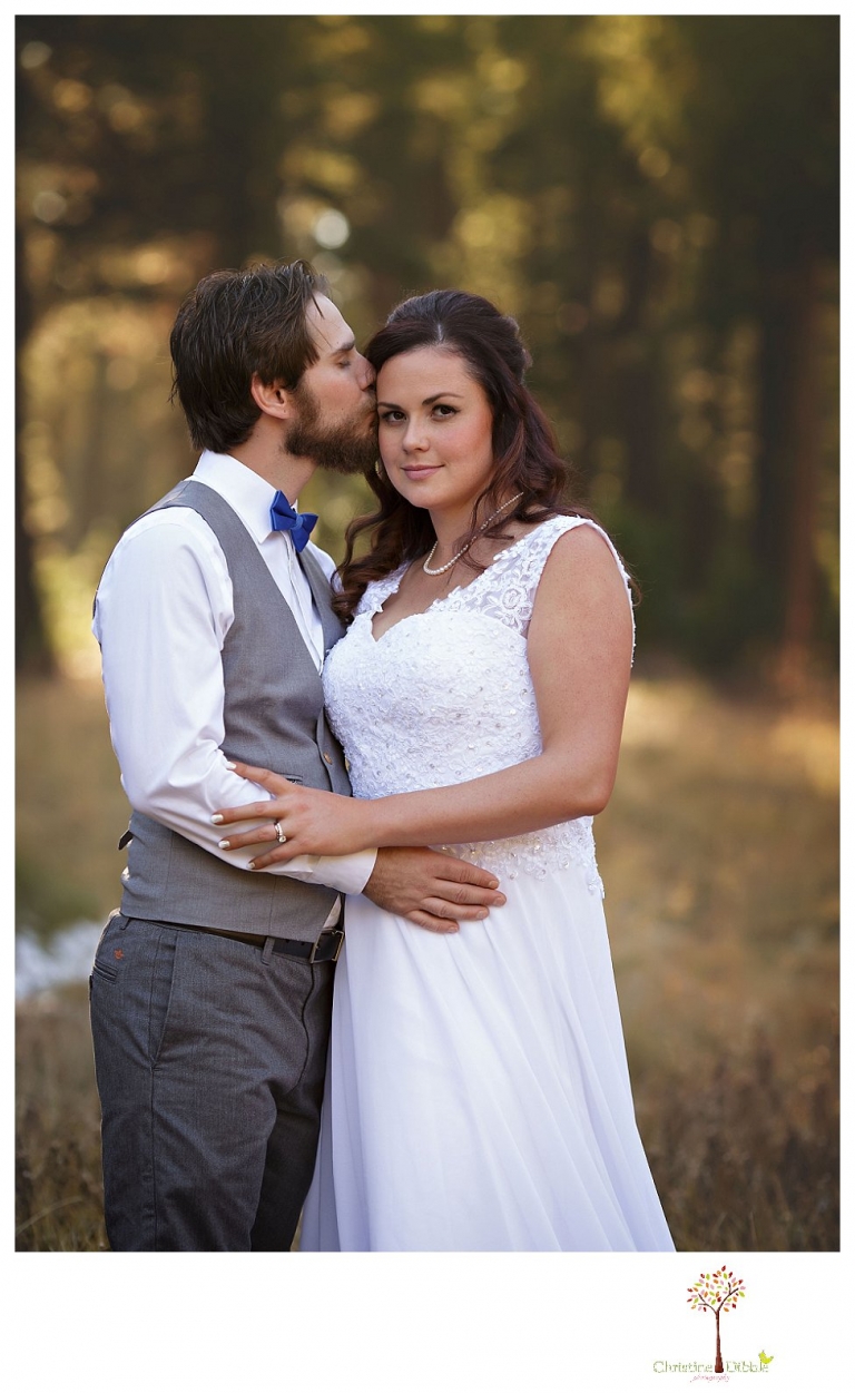 Sonora and Pinecrest wedding photographer Christine Dibble Photography takes wedding photos at a Pinecrest elopement including the groom kissing the bride's cheek in a wooded field.