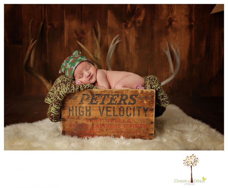 Sonora Newborn Photographer Christine Dibble Photography takes newborn portraits with a hunting camoflage theme including trophy antlers, a vintage wooden shot box and furs.