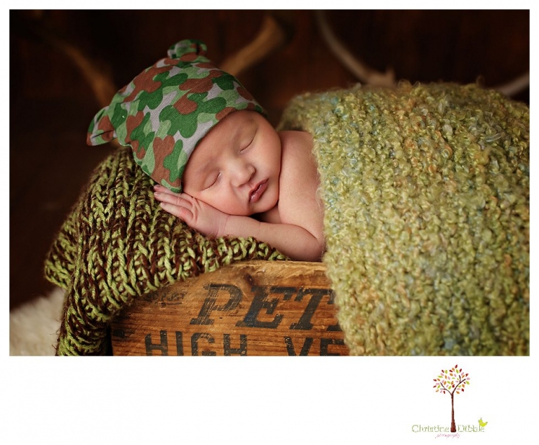 Sonora Newborn Photographer Christine Dibble Photography takes newborn portraits with a hunting camoflage theme including trophy antlers, a vintage wooden shot box and furs.