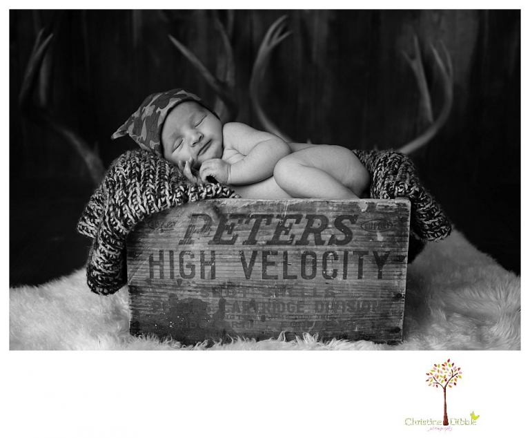 Sonora Newborn Photographer Christine Dibble Photography takes newborn portraits with a hunting camoflage theme including trophy antlers, a vintage wooden shot box and furs.