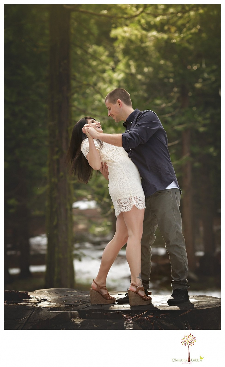 Sonora engagement and wedding photographer Christine Dibble Photography takes engagement photos of a couple in the woods at Pinecrest as they dance on a stump and walk through the trails. 