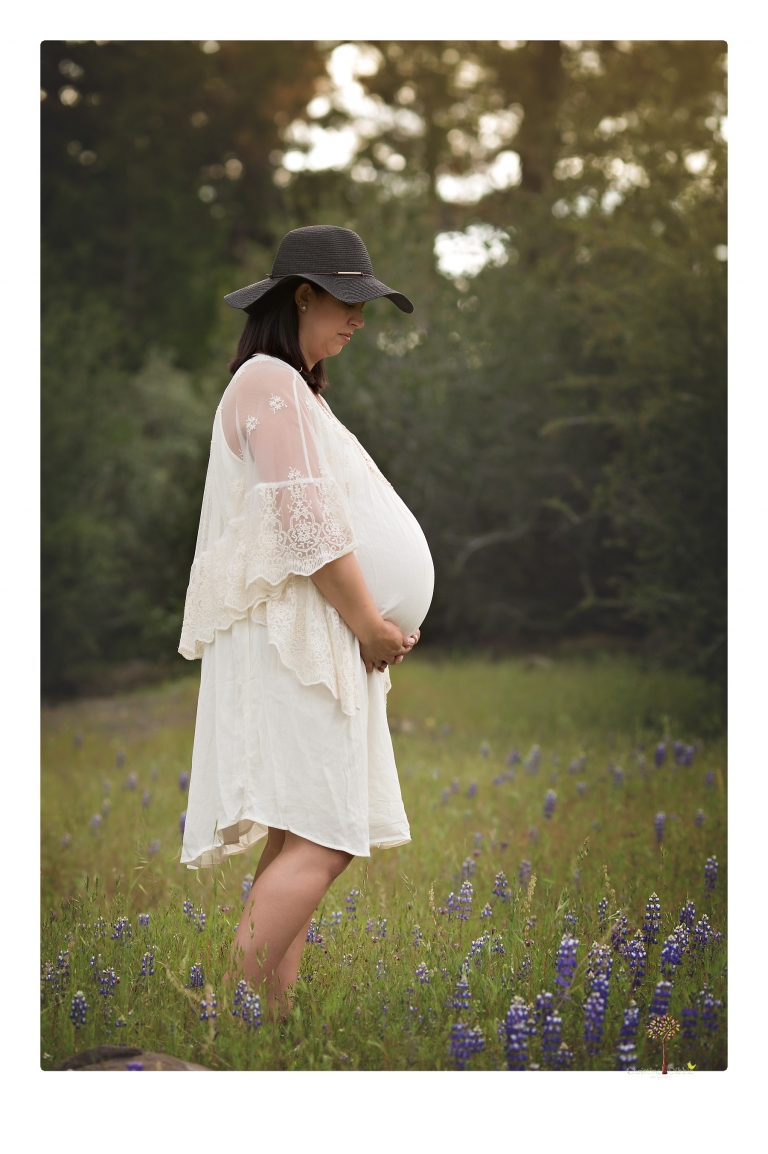 Sonora Maternity Photographer Christine Dibble Photography takes beautiful belly portraits of a mom-to-be pregnant with her fourth child in a white dress and floppy sunhat in a field of Lupine in Twain Harte.
