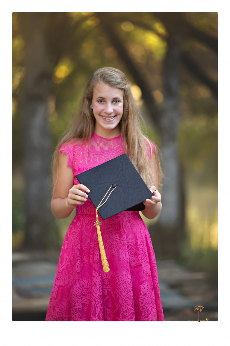 Sonora graduation photographer Christine Dibble Photography takes eighth grade graduation portraits of a girl in a pink lace dress, jeans and cowboy boots with her family, dogs, and steer, Big Mac in her family's yard.