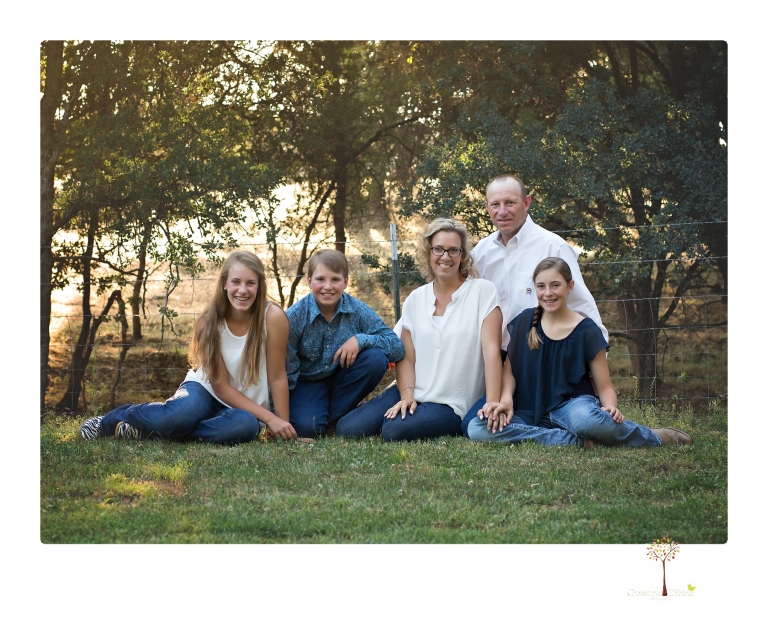 Sonora graduation photographer Christine Dibble Photography takes eighth grade graduation portraits of a girl in a pink lace dress, jeans and cowboy boots with her family, dogs, and steer, Big Mac in her family's yard.