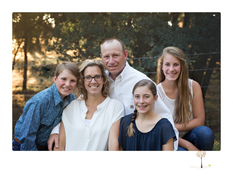 Sonora graduation photographer Christine Dibble Photography takes eighth grade graduation portraits of a girl in a pink lace dress, jeans and cowboy boots with her family, dogs, and steer, Big Mac in her family's yard.