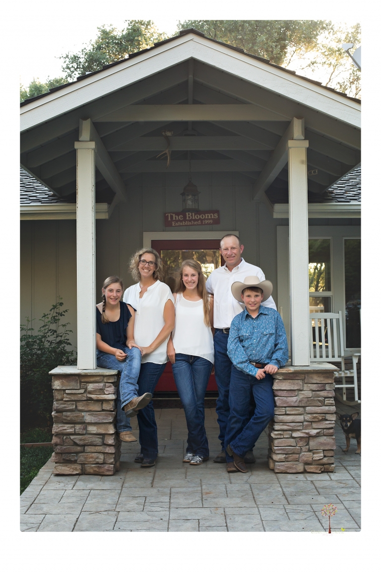Sonora graduation photographer Christine Dibble Photography takes eighth grade graduation portraits of a girl in a pink lace dress, jeans and cowboy boots with her family, dogs, and steer, Big Mac in her family's yard.