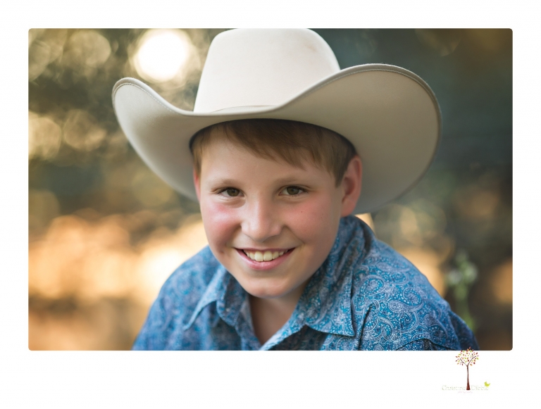 Sonora graduation photographer Christine Dibble Photography takes eighth grade graduation portraits of a girl in a pink lace dress, jeans and cowboy boots with her family, dogs, and steer, Big Mac in her family's yard.