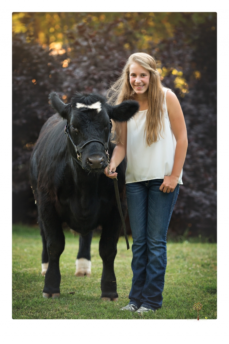 Sonora graduation photographer Christine Dibble Photography takes eighth grade graduation portraits of a girl in a pink lace dress, jeans and cowboy boots with her family, dogs, and steer, Big Mac in her family's yard.