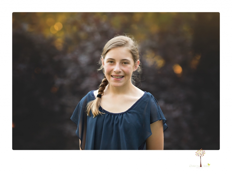 Sonora graduation photographer Christine Dibble Photography takes eighth grade graduation portraits of a girl in a pink lace dress, jeans and cowboy boots with her family, dogs, and steer, Big Mac in her family's yard.