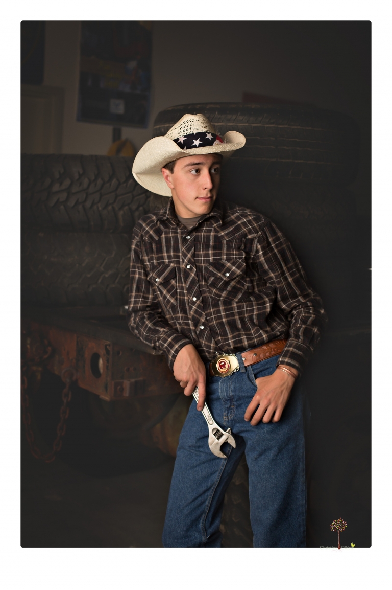Summerville Senior Portraits taken by Christine Dibble Photography of Sonora in the auto shop with a senior boy's 1959 Jeep Willys pick-up truck and his letterman jacket.