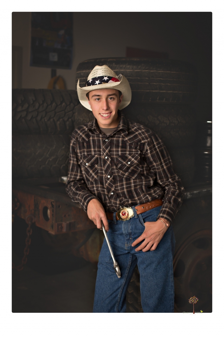 Summerville Senior Portraits taken by Christine Dibble Photography of Sonora in the auto shop with a senior boy's 1959 Jeep Willys pick-up truck and his letterman jacket.